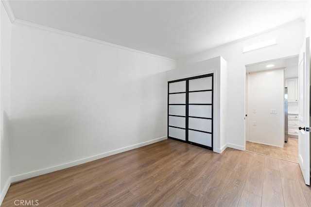 unfurnished bedroom featuring light hardwood / wood-style floors and crown molding