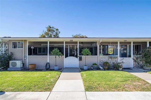 view of front of home with a front yard and ac unit