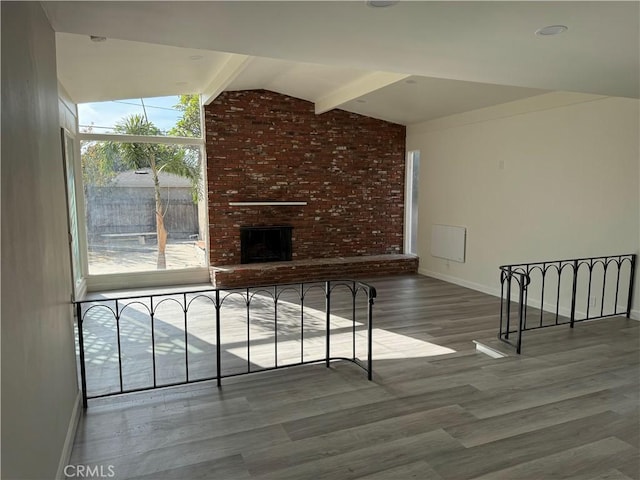 unfurnished living room featuring hardwood / wood-style floors, lofted ceiling with beams, and a fireplace