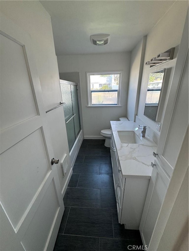 bathroom featuring vanity, a shower with shower door, and toilet