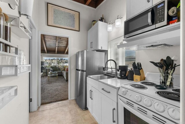 kitchen with stainless steel appliances, sink, wooden ceiling, white cabinets, and light tile patterned flooring