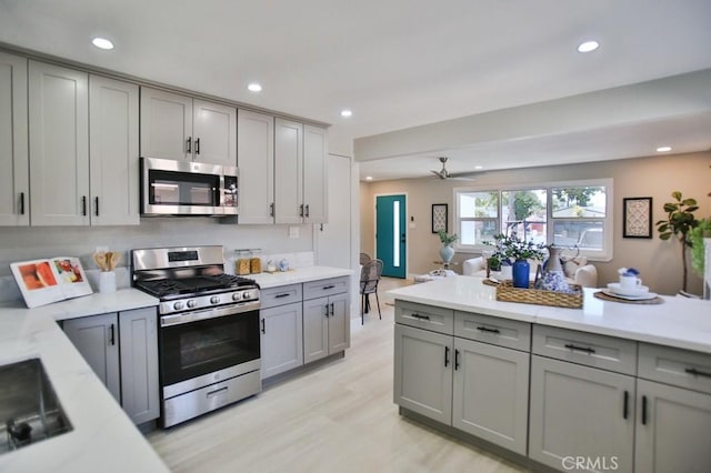 kitchen featuring stainless steel appliances, recessed lighting, gray cabinets, and light wood-style flooring