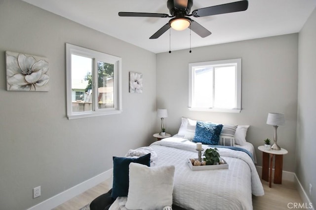 bedroom with a ceiling fan, light wood-style flooring, and baseboards