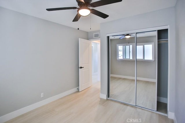 unfurnished bedroom featuring ceiling fan, wood finished floors, visible vents, baseboards, and a closet