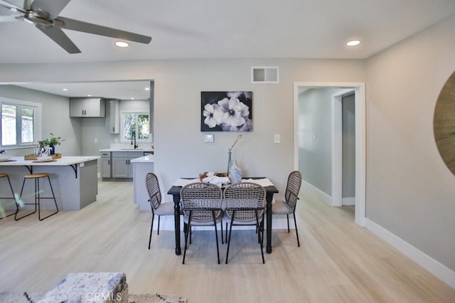 dining area with light wood finished floors, a wealth of natural light, visible vents, and baseboards