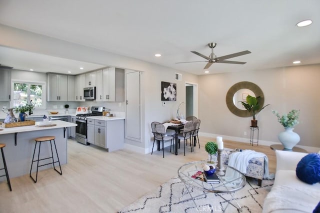 living area with recessed lighting, a ceiling fan, baseboards, visible vents, and light wood-style floors