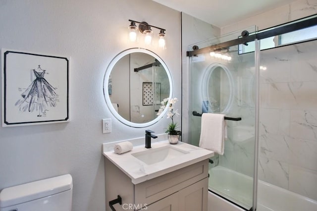 bathroom featuring enclosed tub / shower combo, a textured wall, vanity, and toilet