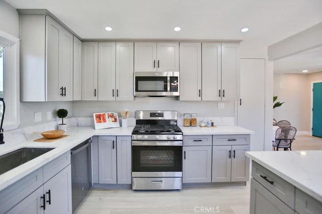 kitchen featuring stainless steel appliances, recessed lighting, gray cabinets, and light stone counters