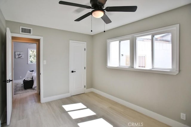 unfurnished bedroom featuring a ceiling fan, light wood-type flooring, visible vents, and baseboards