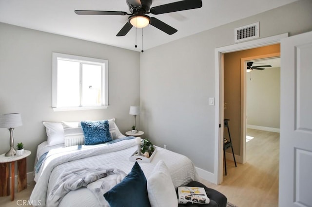 bedroom with light wood-style floors, visible vents, baseboards, and a ceiling fan