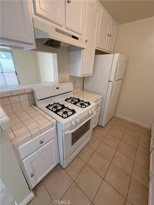 kitchen featuring tile counters, white cabinets, light tile patterned flooring, and white appliances