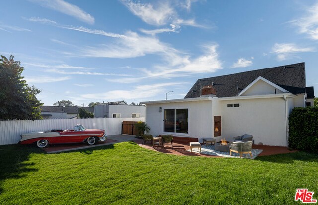 back of property featuring a patio area, an outdoor fire pit, and a lawn