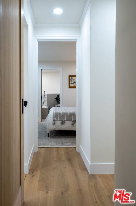 hallway featuring light wood-type flooring and ornamental molding