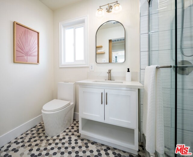 bathroom featuring tile patterned floors, toilet, a shower with door, and vanity