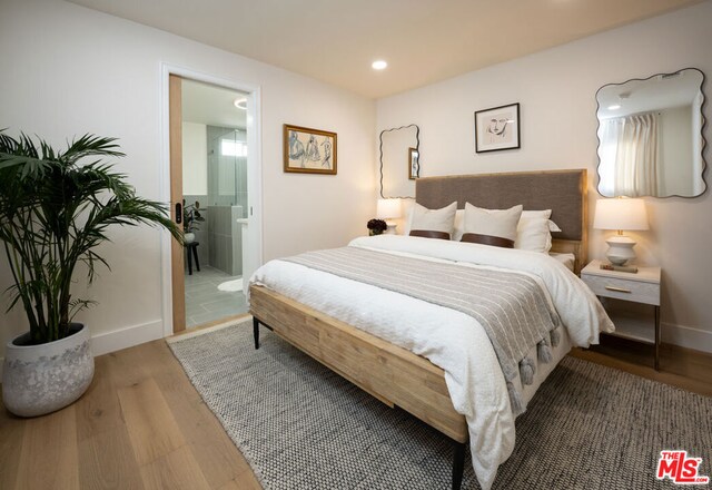 bedroom with connected bathroom and wood-type flooring