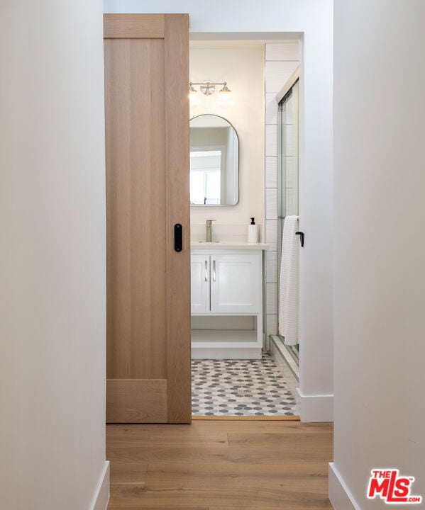 bathroom with hardwood / wood-style floors, vanity, and an enclosed shower