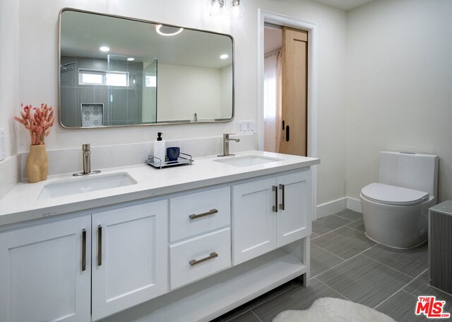 bathroom with toilet, vanity, and tile patterned flooring