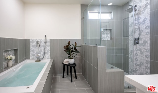 bathroom featuring tile walls, tile patterned floors, and a tile shower