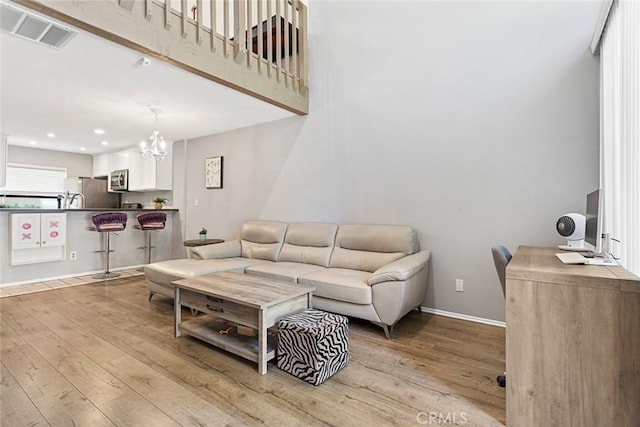 living room with light hardwood / wood-style floors and an inviting chandelier