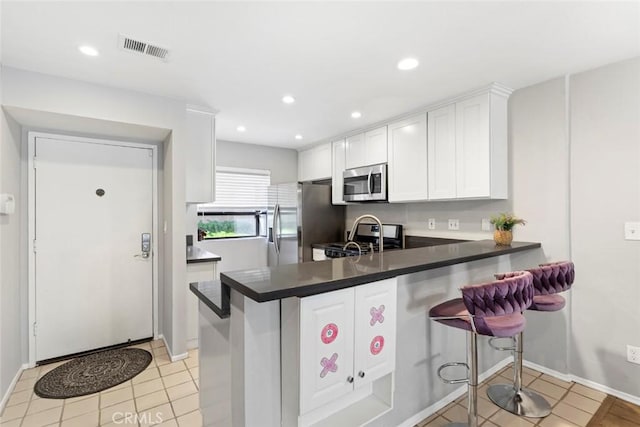 kitchen with a breakfast bar area, kitchen peninsula, white cabinetry, and stainless steel appliances