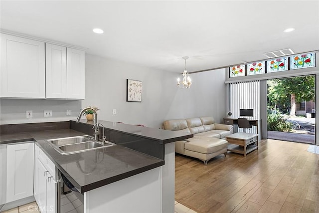 kitchen with kitchen peninsula, white cabinetry, sink, and pendant lighting