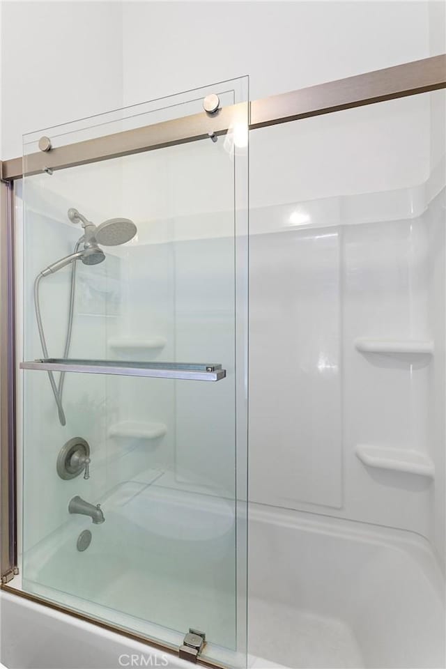 bathroom featuring combined bath / shower with glass door