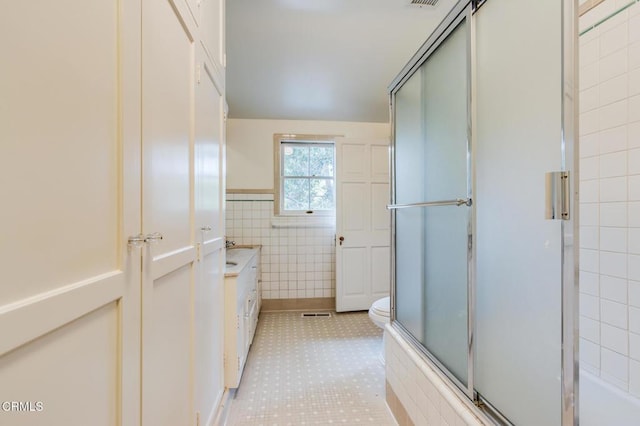 bathroom featuring tile walls, vanity, a shower with door, and toilet