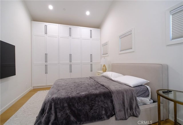 bedroom with lofted ceiling and light wood-type flooring