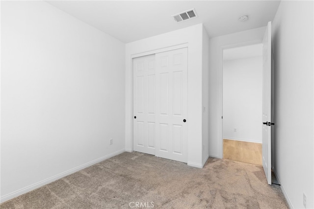 unfurnished bedroom featuring light carpet and a closet