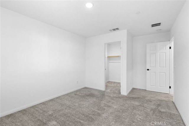 unfurnished bedroom with a spacious closet, light carpet, and a closet