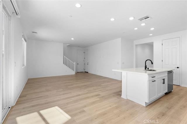 kitchen featuring sink, light hardwood / wood-style flooring, stainless steel dishwasher, and an island with sink