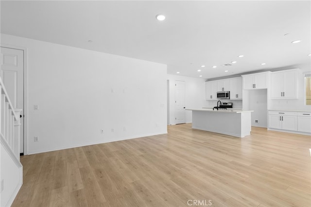 unfurnished living room featuring light hardwood / wood-style flooring and sink