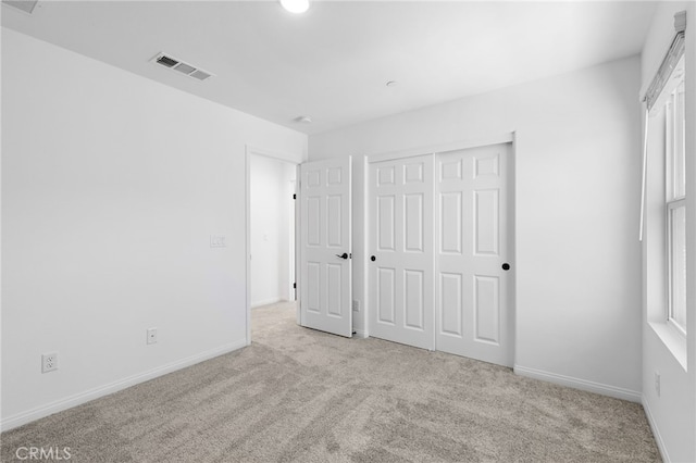 unfurnished bedroom featuring light colored carpet and a closet