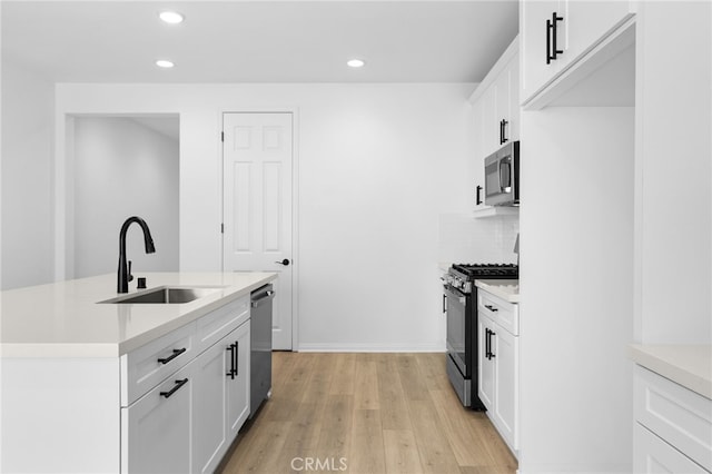 kitchen with appliances with stainless steel finishes, white cabinetry, light hardwood / wood-style flooring, and sink