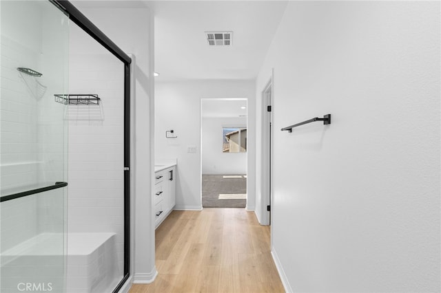 bathroom with hardwood / wood-style flooring, vanity, and a shower with door