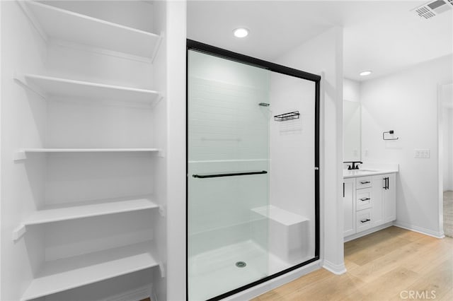 bathroom with hardwood / wood-style floors, vanity, and a shower with shower door