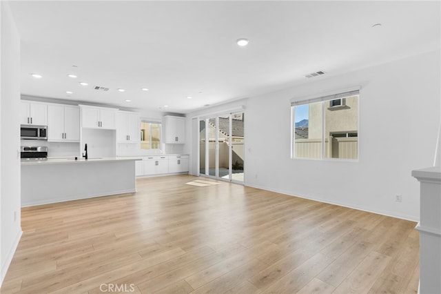 unfurnished living room featuring light hardwood / wood-style flooring and sink