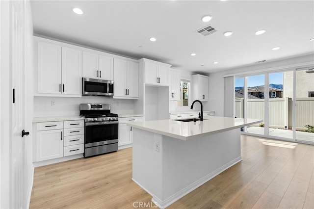 kitchen with light hardwood / wood-style floors, sink, white cabinetry, and stainless steel appliances