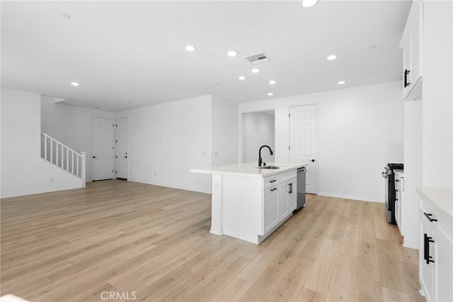 kitchen featuring white cabinets, sink, an island with sink, light hardwood / wood-style floors, and stainless steel appliances