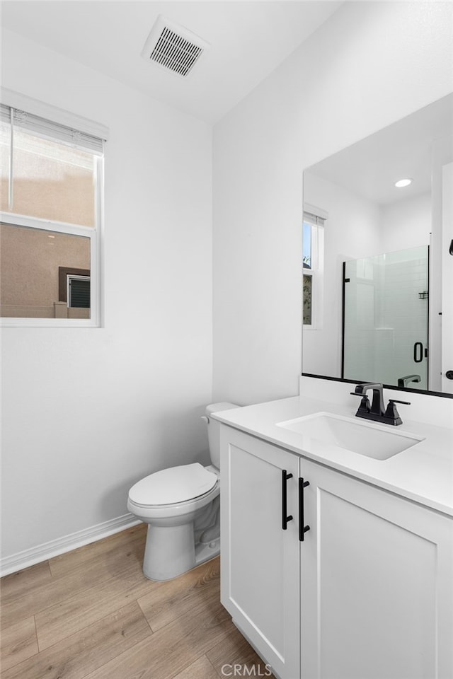 bathroom featuring toilet, vanity, wood-type flooring, and walk in shower