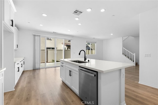 kitchen featuring sink, stainless steel dishwasher, a center island with sink, white cabinets, and light wood-type flooring