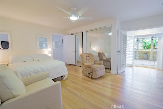 bedroom with two closets, light wood-type flooring, access to outside, and ceiling fan