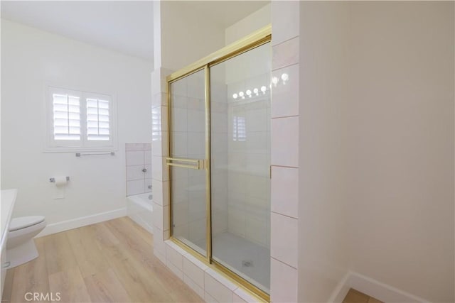 bathroom featuring hardwood / wood-style floors, toilet, and plus walk in shower