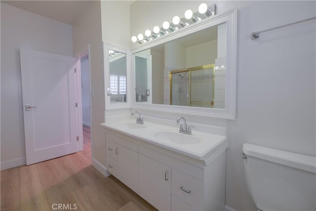 bathroom with walk in shower, hardwood / wood-style floors, vanity, and toilet