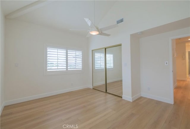 unfurnished bedroom with light wood-type flooring, high vaulted ceiling, a closet, and ceiling fan