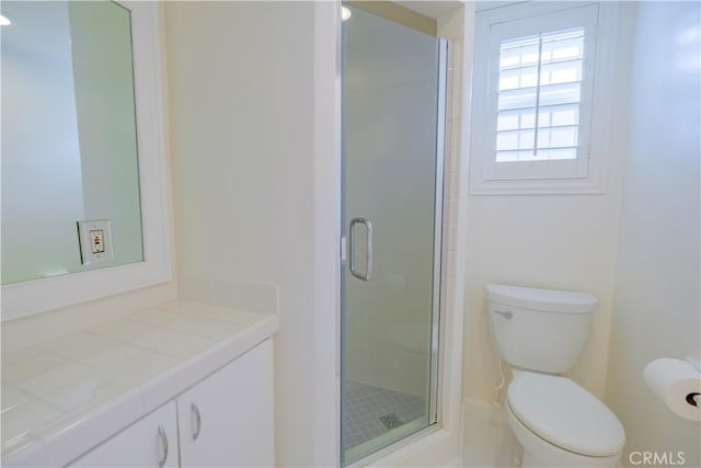 bathroom featuring vanity, a shower with shower door, and toilet