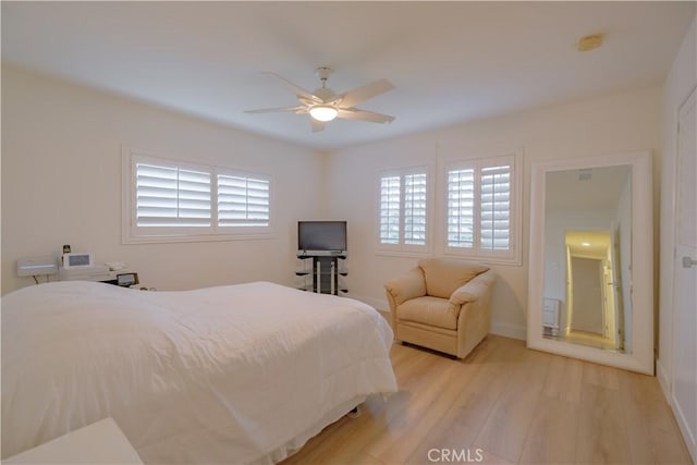 bedroom with ceiling fan, light hardwood / wood-style floors, and multiple windows