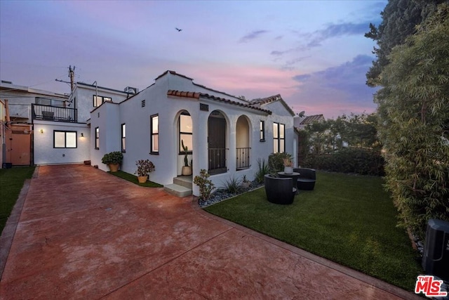 view of front of property featuring a yard and a balcony