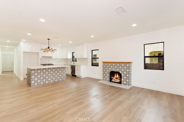 living room with a chandelier, a tiled fireplace, and light hardwood / wood-style flooring