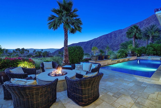 patio terrace at dusk with a mountain view and an outdoor living space with a fire pit